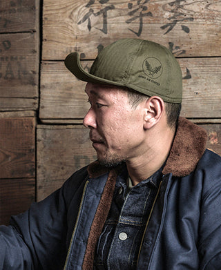 Olive cloth military cap with front insignia and curved brim