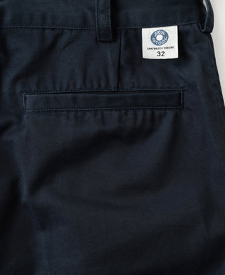 Navy cotton twill trousers detail: straight front pocket flaps and belt-loop waistband.