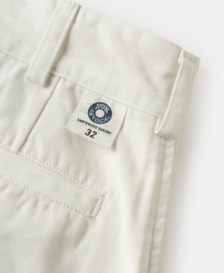 White cotton twill trousers with brand patch, belt loops, and double-pleat detail