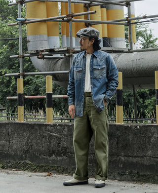 Olive fatigue trousers on wearer, full-length side profile with wide legs