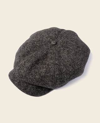 Dark gray herringbone wool newsboy cap with stitched crown and curved brim.