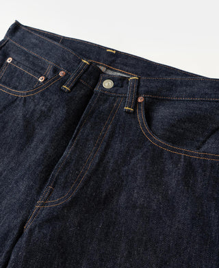 Waistband and front pockets of indigo denim jeans with button closure