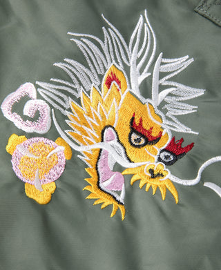 Close-up of olive fabric with colorful dragon embroidery and white wing details