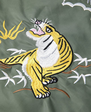 Close-up of olive fabric with tiger embroidery on leafy vine background