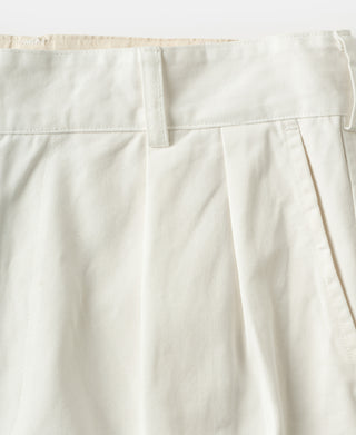 White cotton twill trousers with front pleats, waistband, and belt loops.