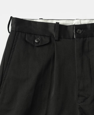 Black cotton twill trousers with pleats and buttoned pocket at hip