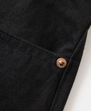 Black denim jeans close-up: side seam and copper button at pocket