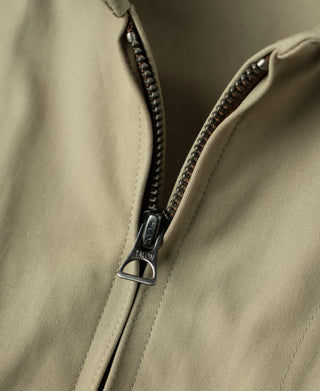Khaki flight jacket zipper close-up with metal pull and braided stitch trim