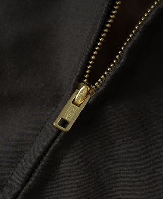 Gold-tone zipper with chain teeth on black bomber jacket, close-up detail
