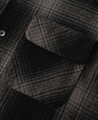 Two chest pockets on black and gray ombre check sports shirt, angled close-up
