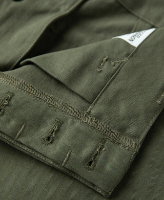 Olive pants cuff with side seam stitching and pocket tab detail.