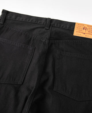 Black denim jeans front close-up with two pockets and orange care label