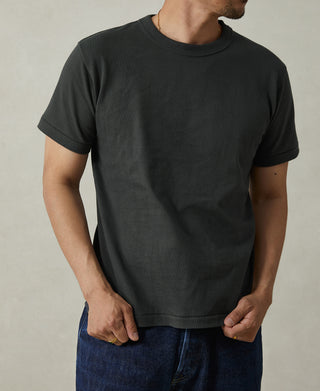 Dark crew-neck athletic T-shirt worn with jeans, short sleeves.