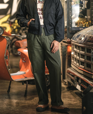 Olive cotton twill trousers worn with cuffed hem and pleated front