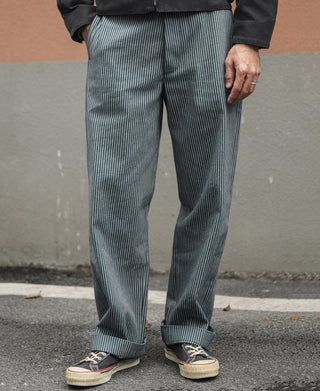 Striped work pants on model, blue-and-white vertical pinstripes and relaxed leg