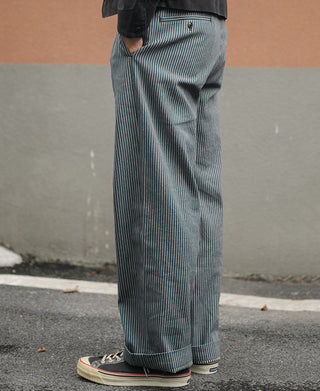 Striped work pants on model from side, blue-and-white vertical pinstripes
